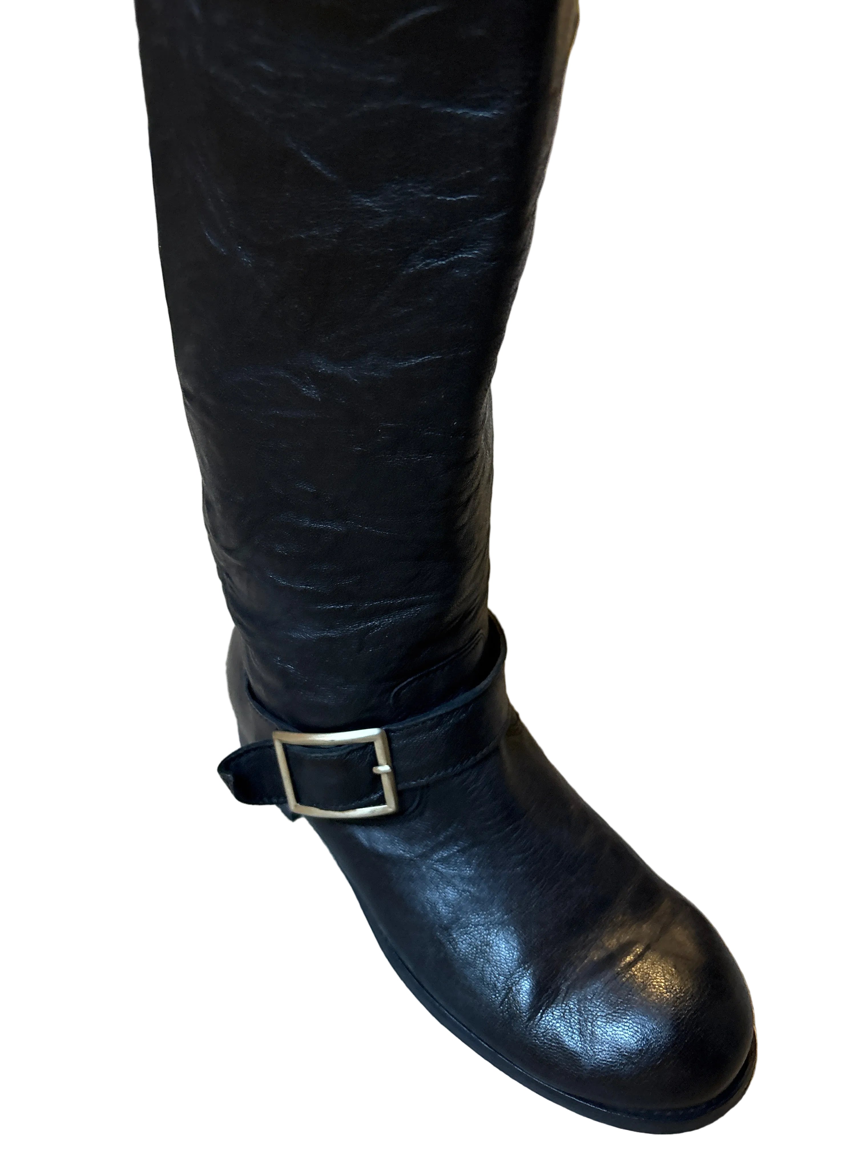 Black leather boot with a buckle on a textured surface