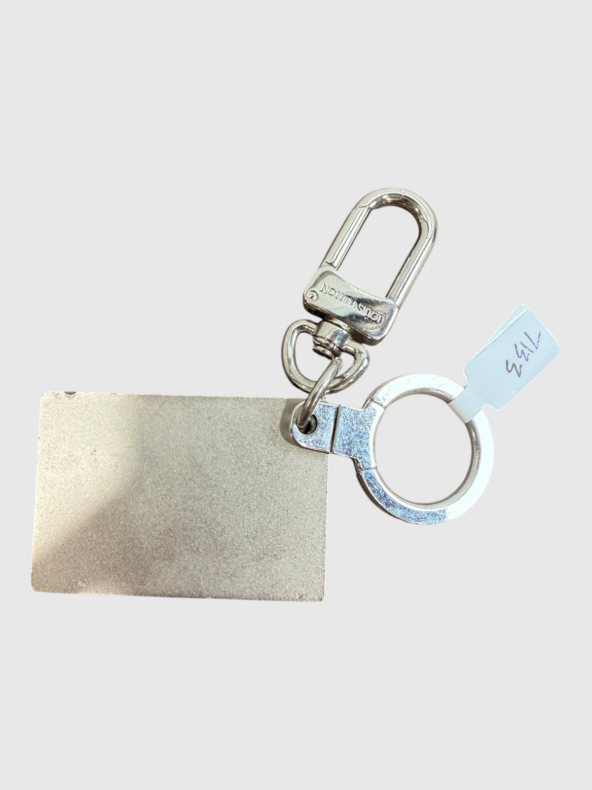 CURATED by Kira Louis Vuitton Traveling Requisites silver keychain bag charm on a wooden surface