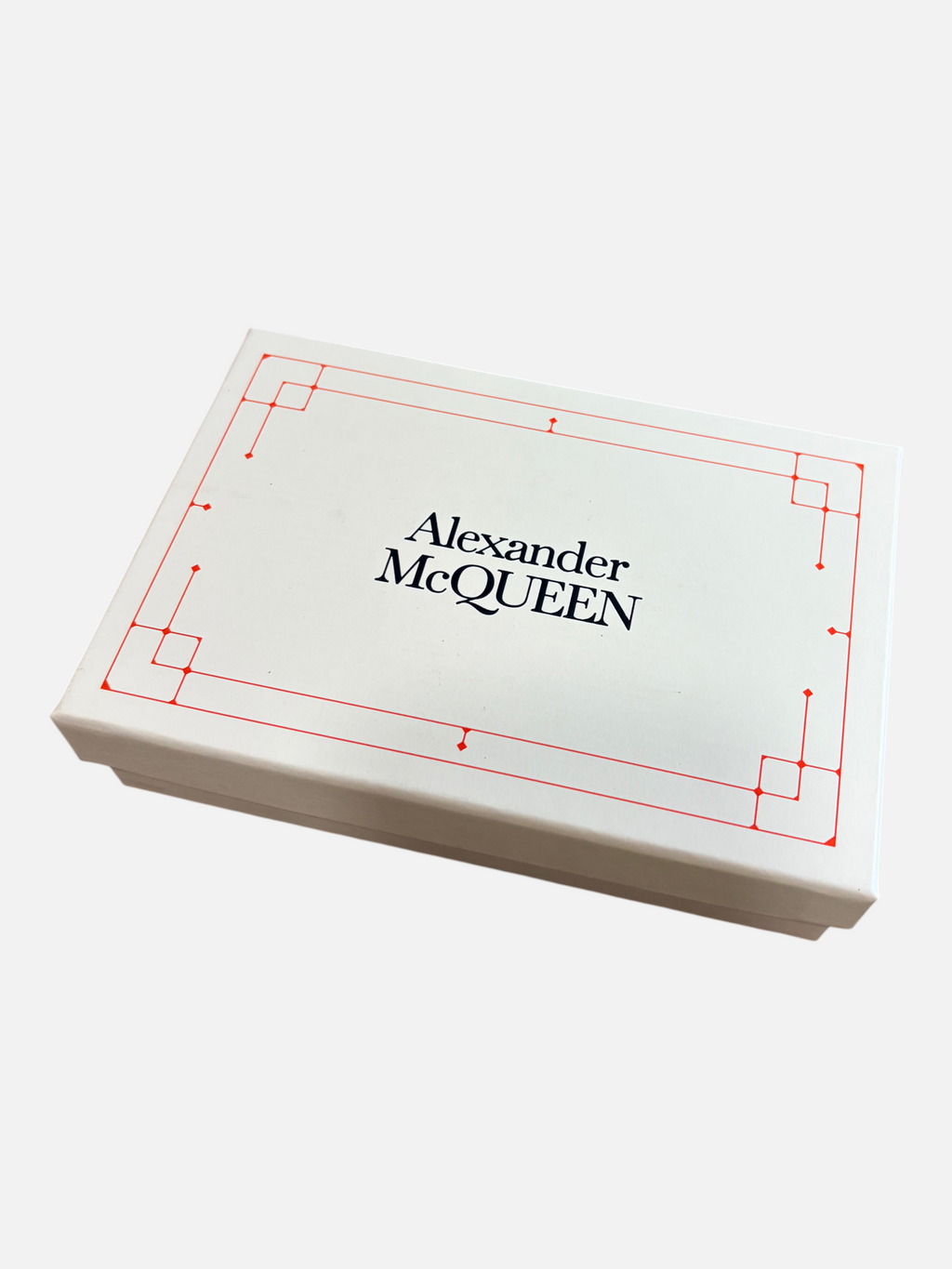 CURATED by Kira Alexander McQueen card holder presentation box with red geometric border on a wooden surface