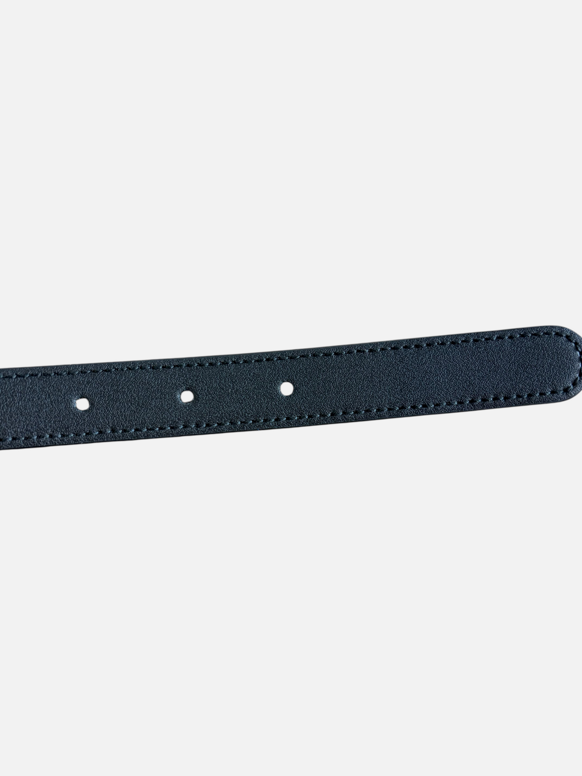 CURATED by Kira black cowhide leather belt strap with detailed stitching on a rustic wooden surface