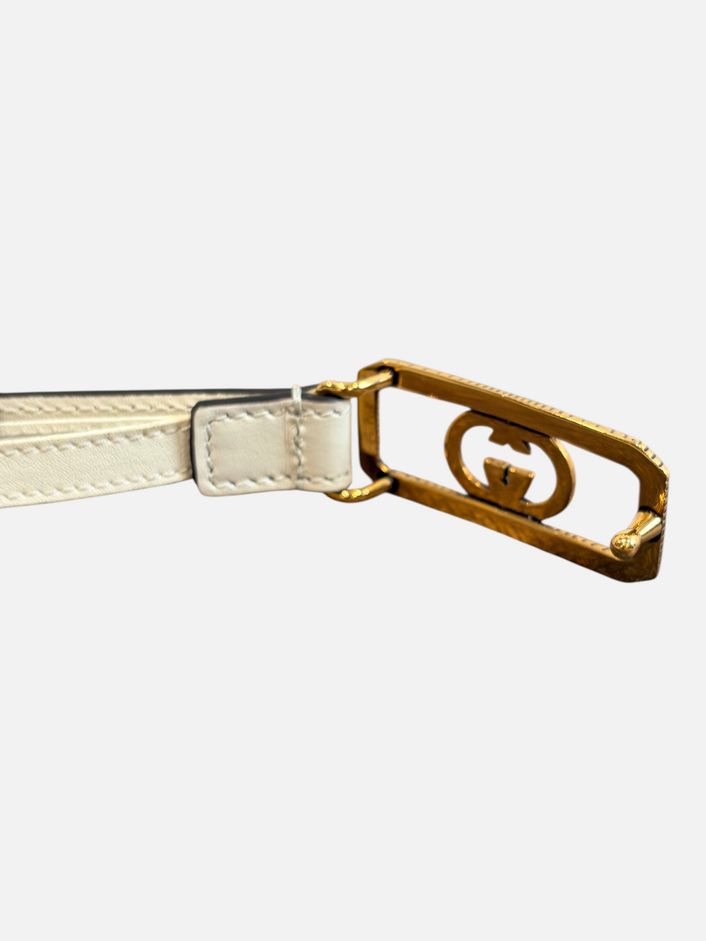 CURATED by Kira Gucci GG buckle leather belt in mystic white with gold-tone hardware on a wooden surface