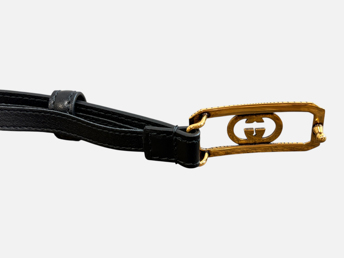 CURATED by Kira Gucci black leather belt featuring a rectangular gold-tone GG logo buckle on a wooden surface
