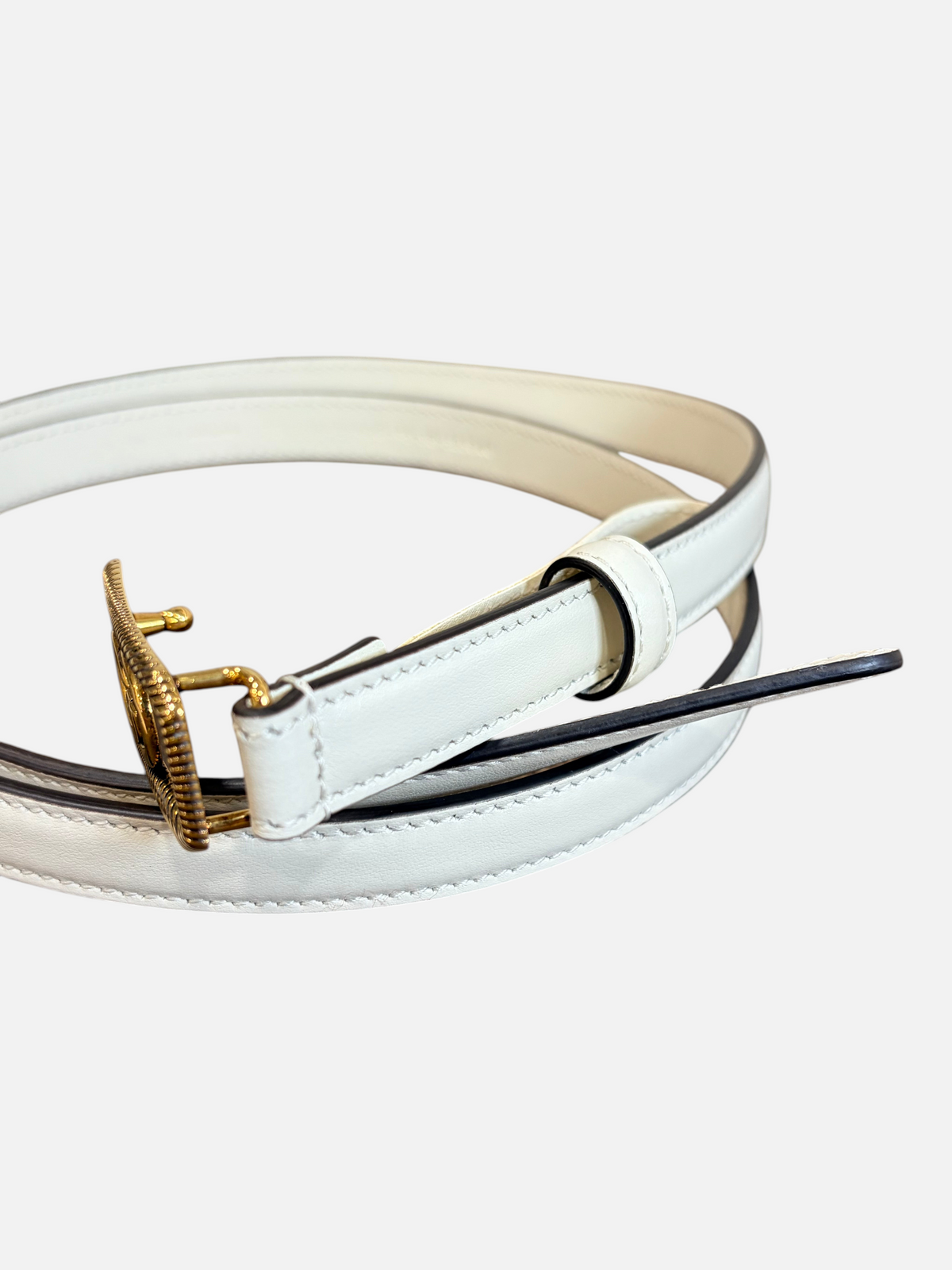 CURATED by Kira Gucci GG leather belt in mystic white with a gold-tone buckle, resting on a wooden surface.