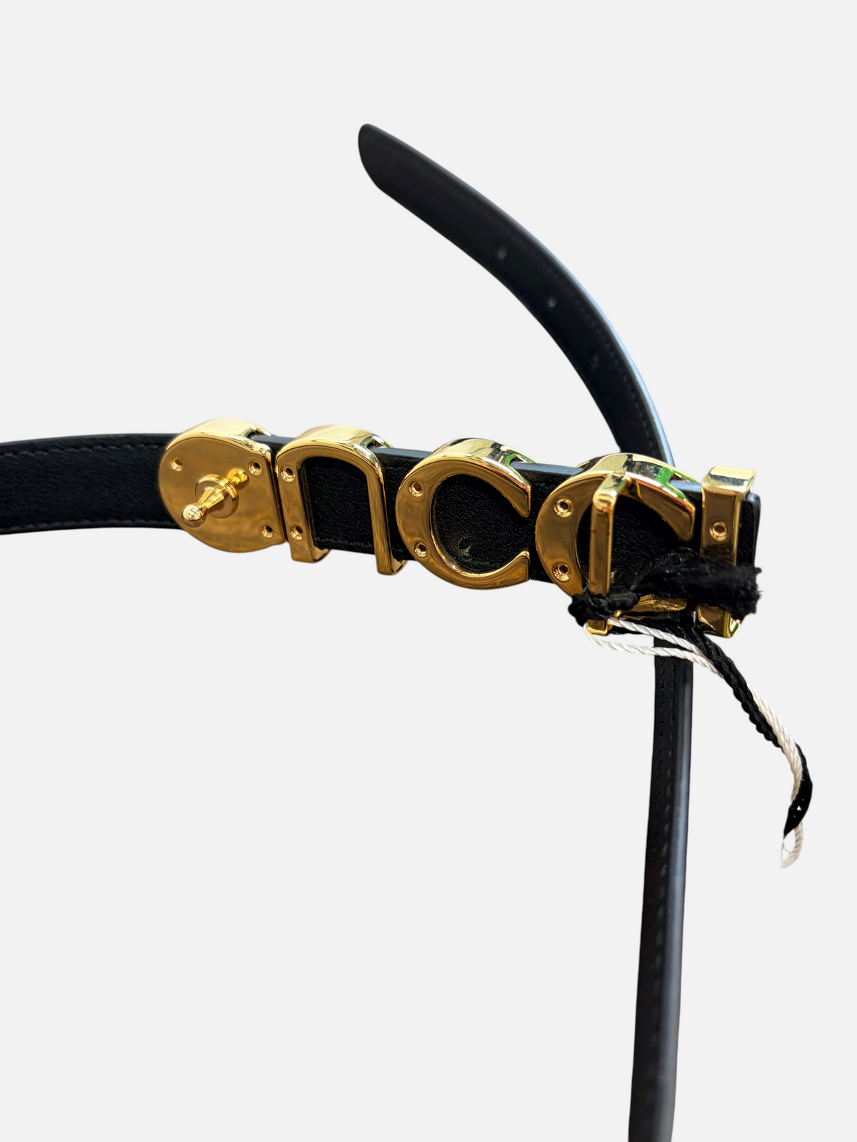 CURATED by Kira Gucci black cowhide leather belt featuring a prominent gold-tone logo buckle on a wooden surface.