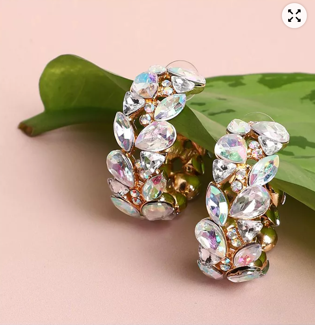 CURATED by Kira gold-plated hoop earrings featuring iridescent teardrop stones on a green leaf background