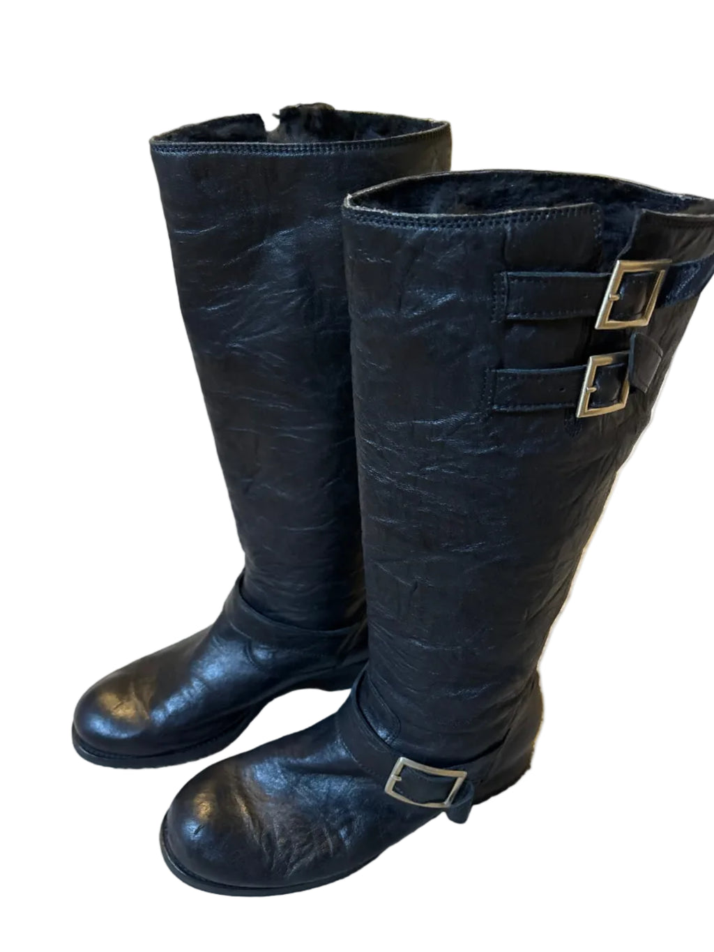 Black leather boots with buckles on a carpeted floor.