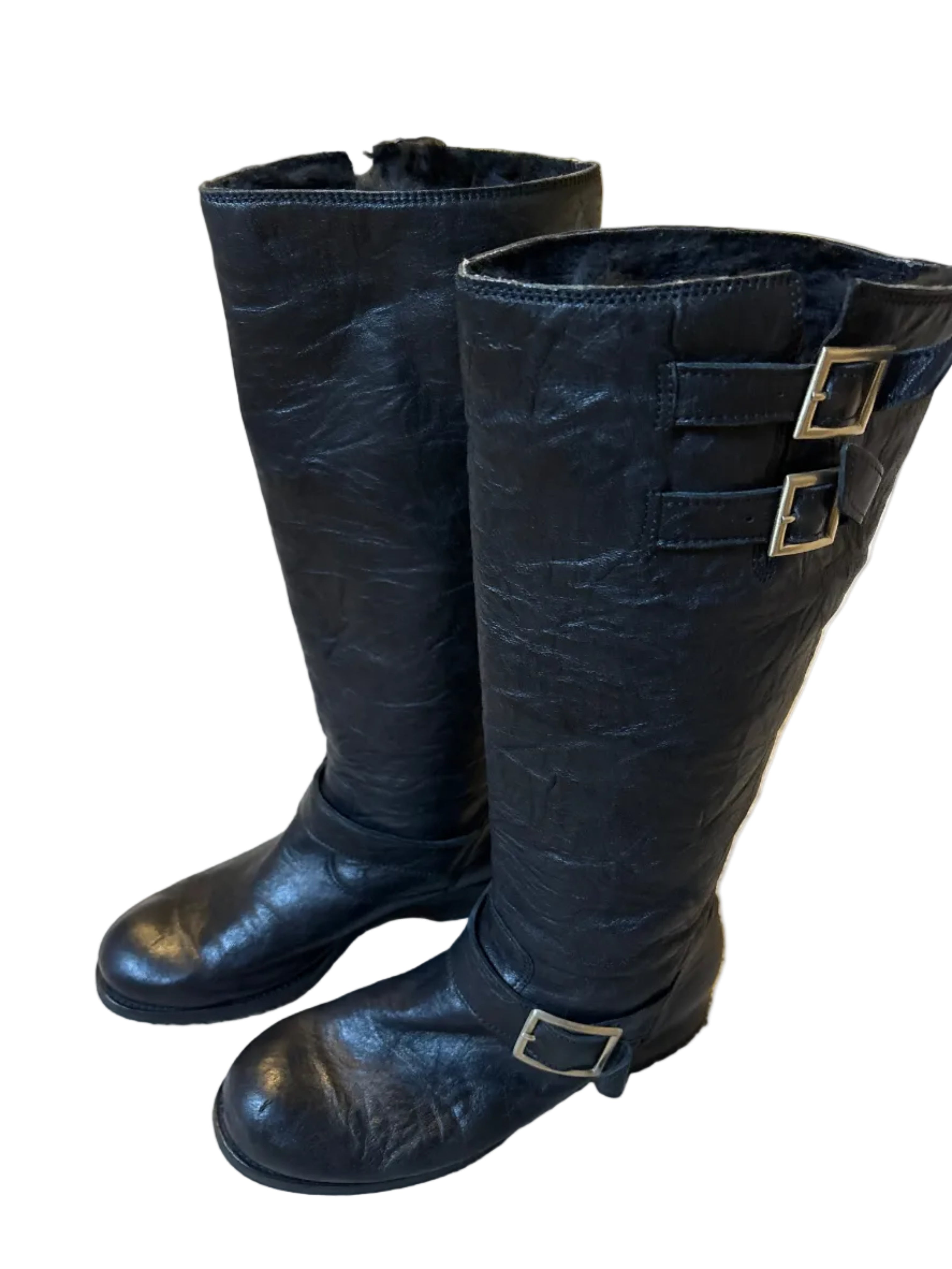 Black leather boots with buckles on a carpeted floor.