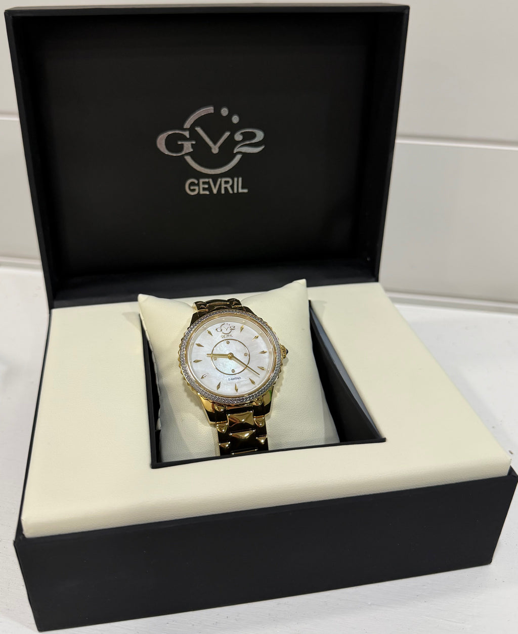 Gold watch in a black GEVRIL box on a white background
