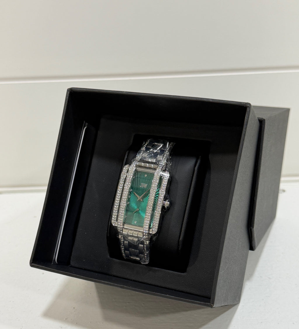 Luxury watch with green face and silver case in a black box on a white surface