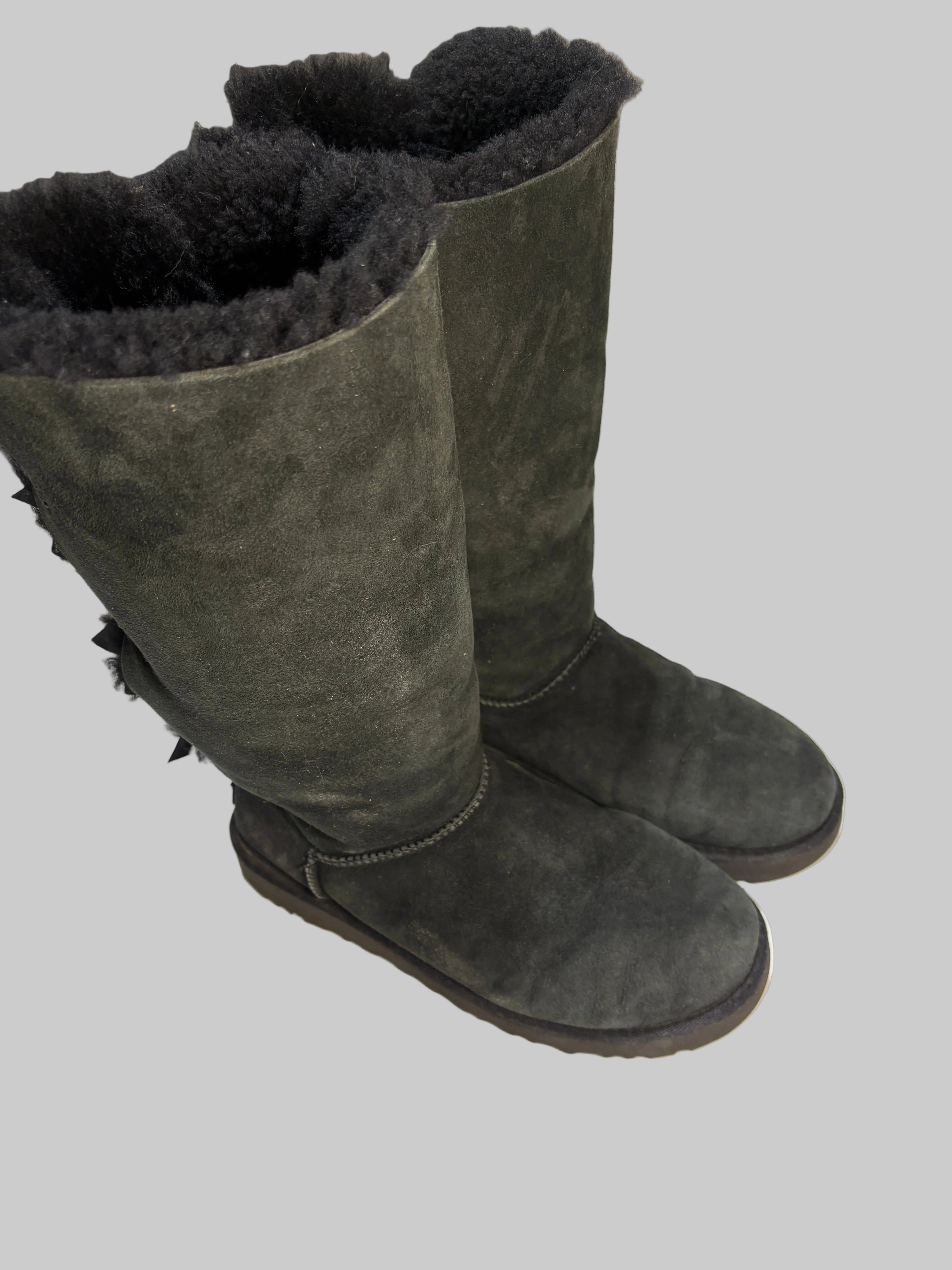 Dark green suede boots with fur lining on a white floor.