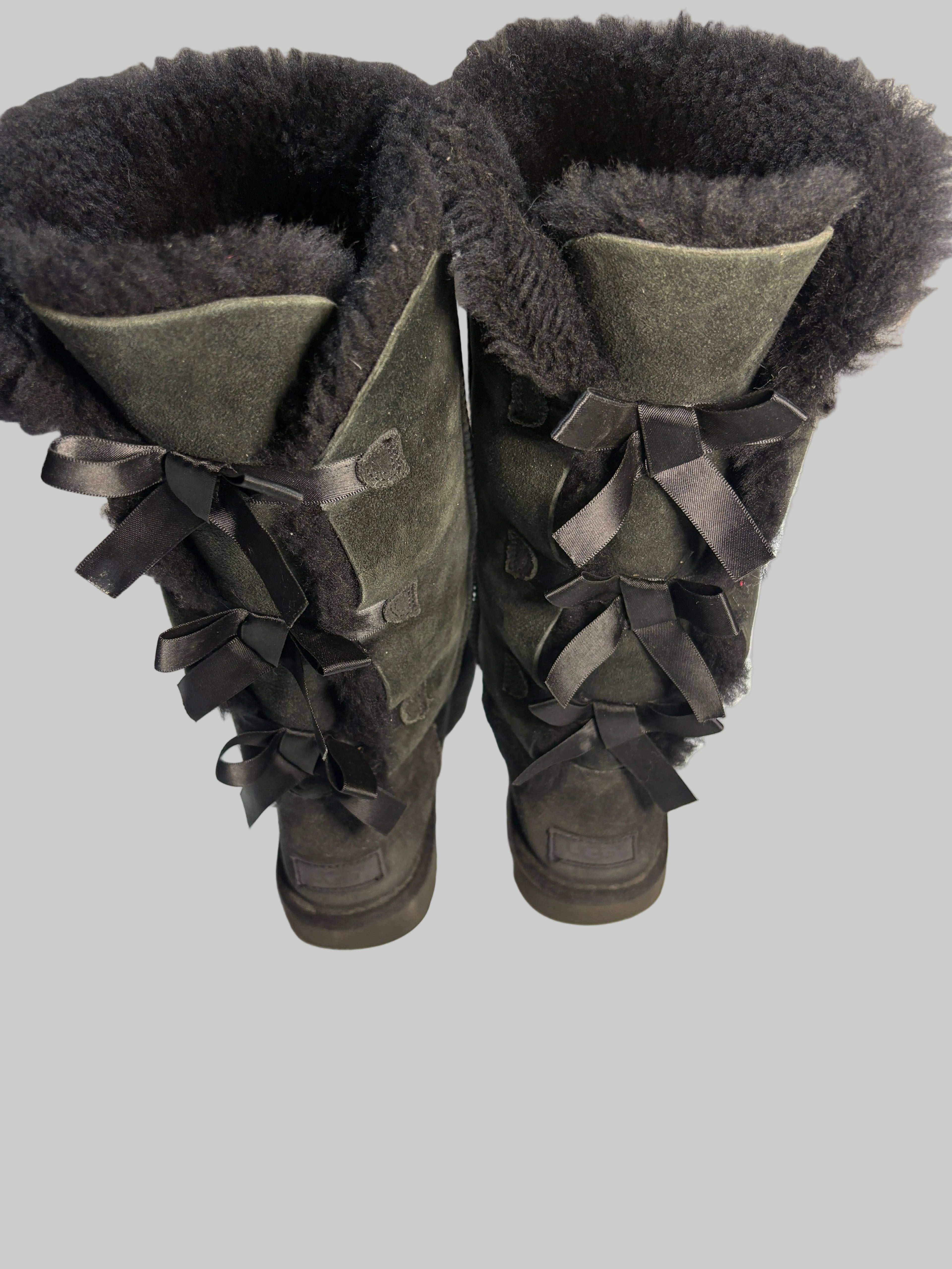 Pair of dark green boots with fur lining on a white surface