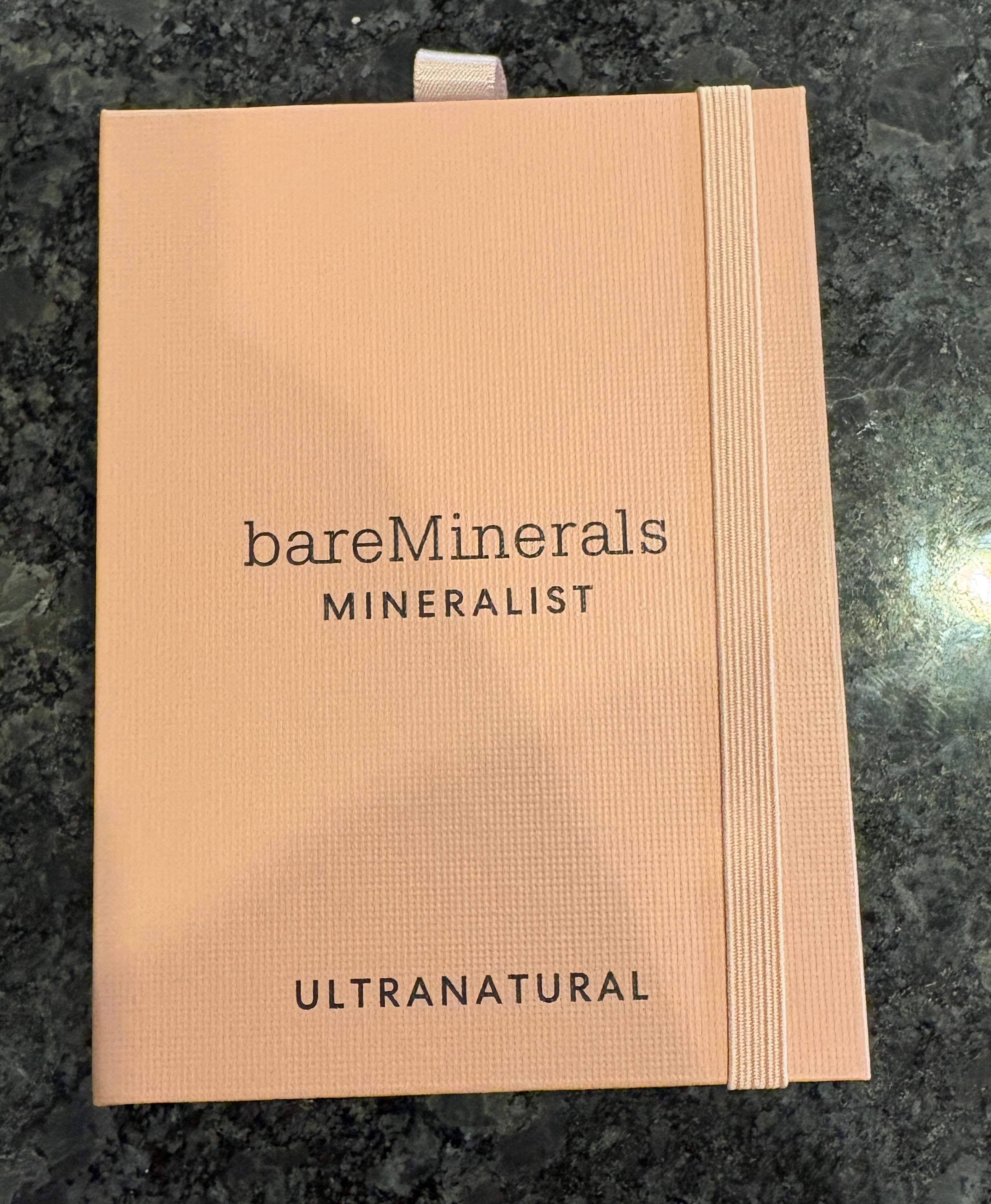 Bare Minerals makeup pouch on a dark granite surface