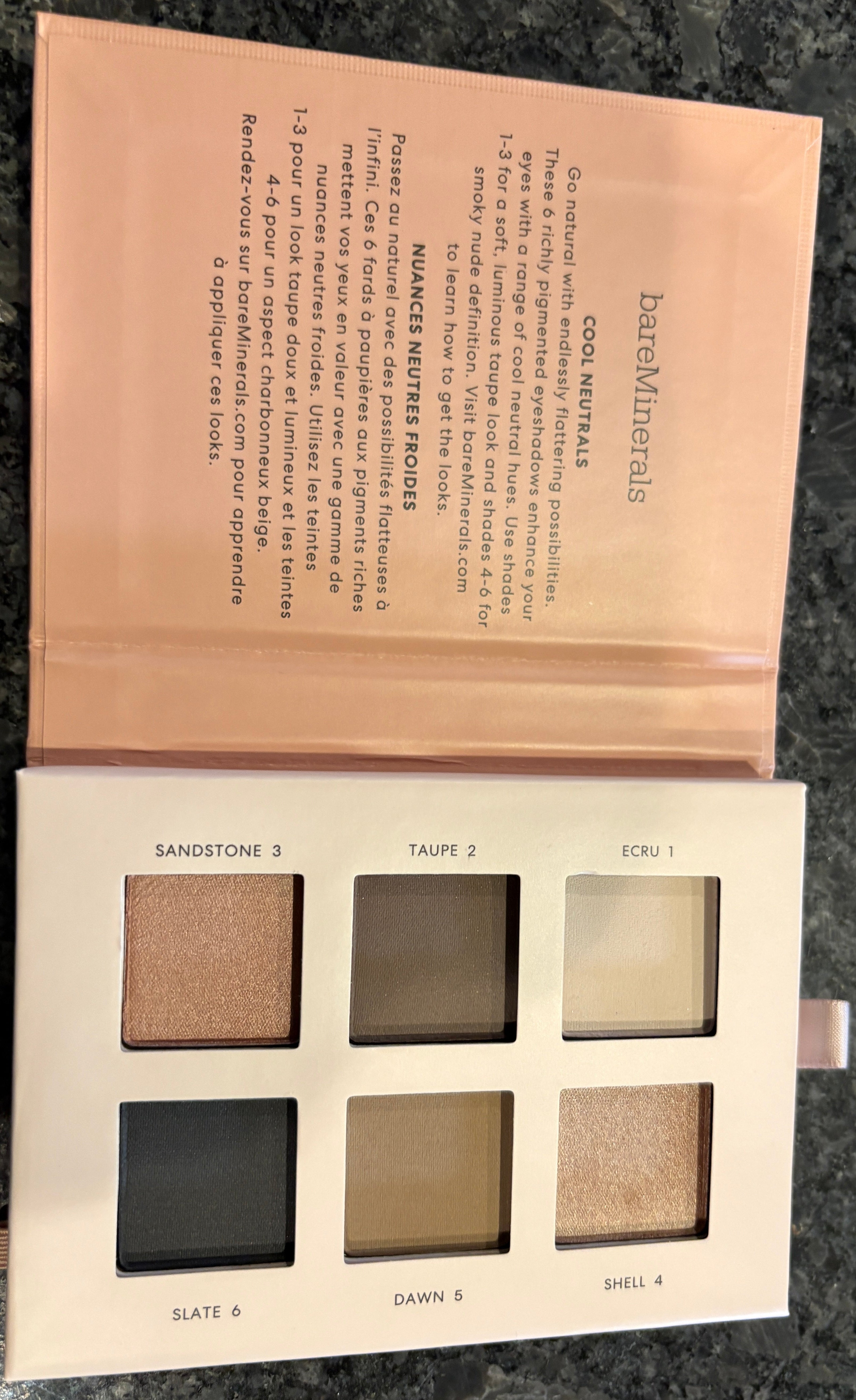 Open makeup palette with six shades on a dark surface