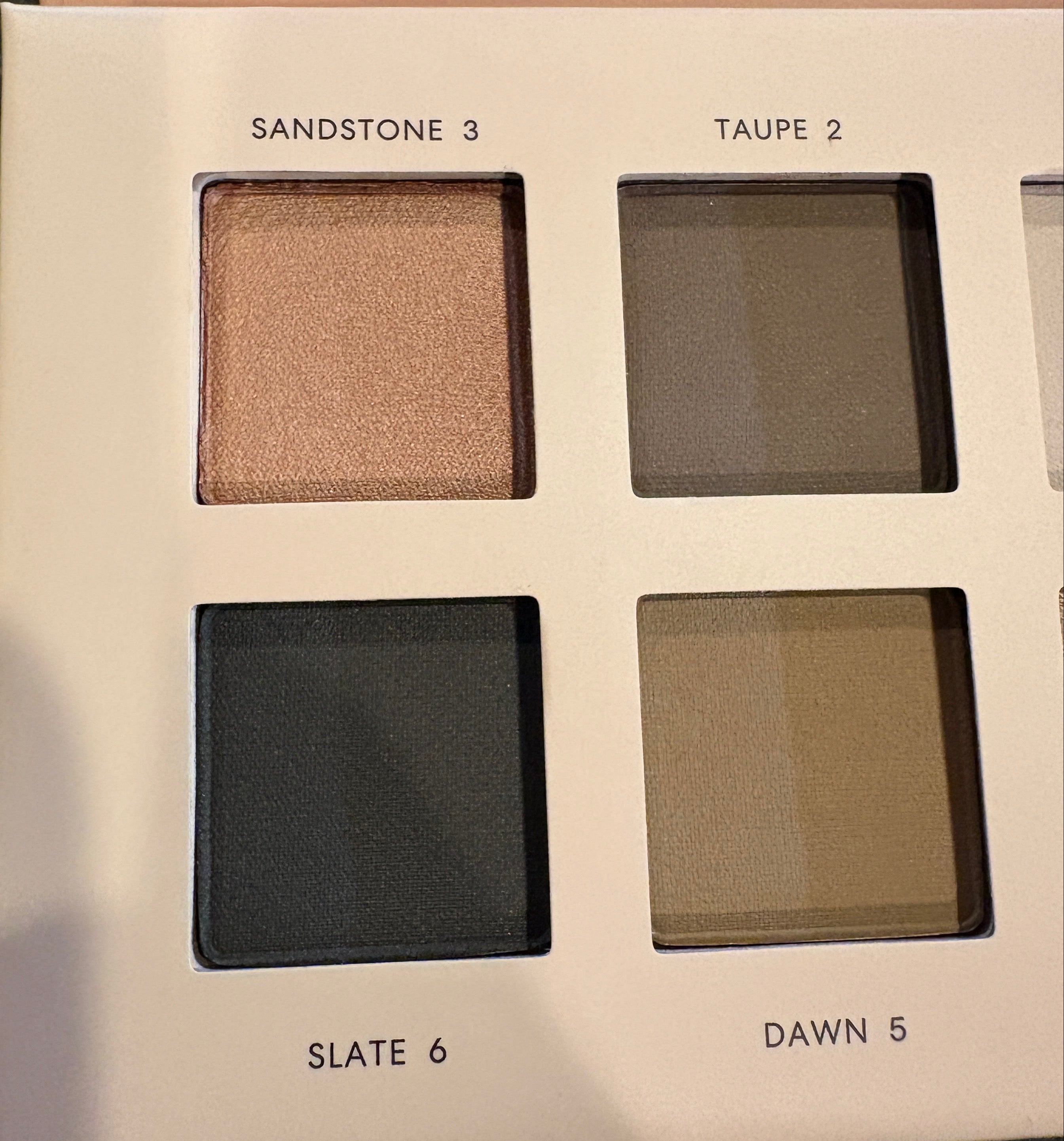 Makeup palette with four color swatches on a dark surface