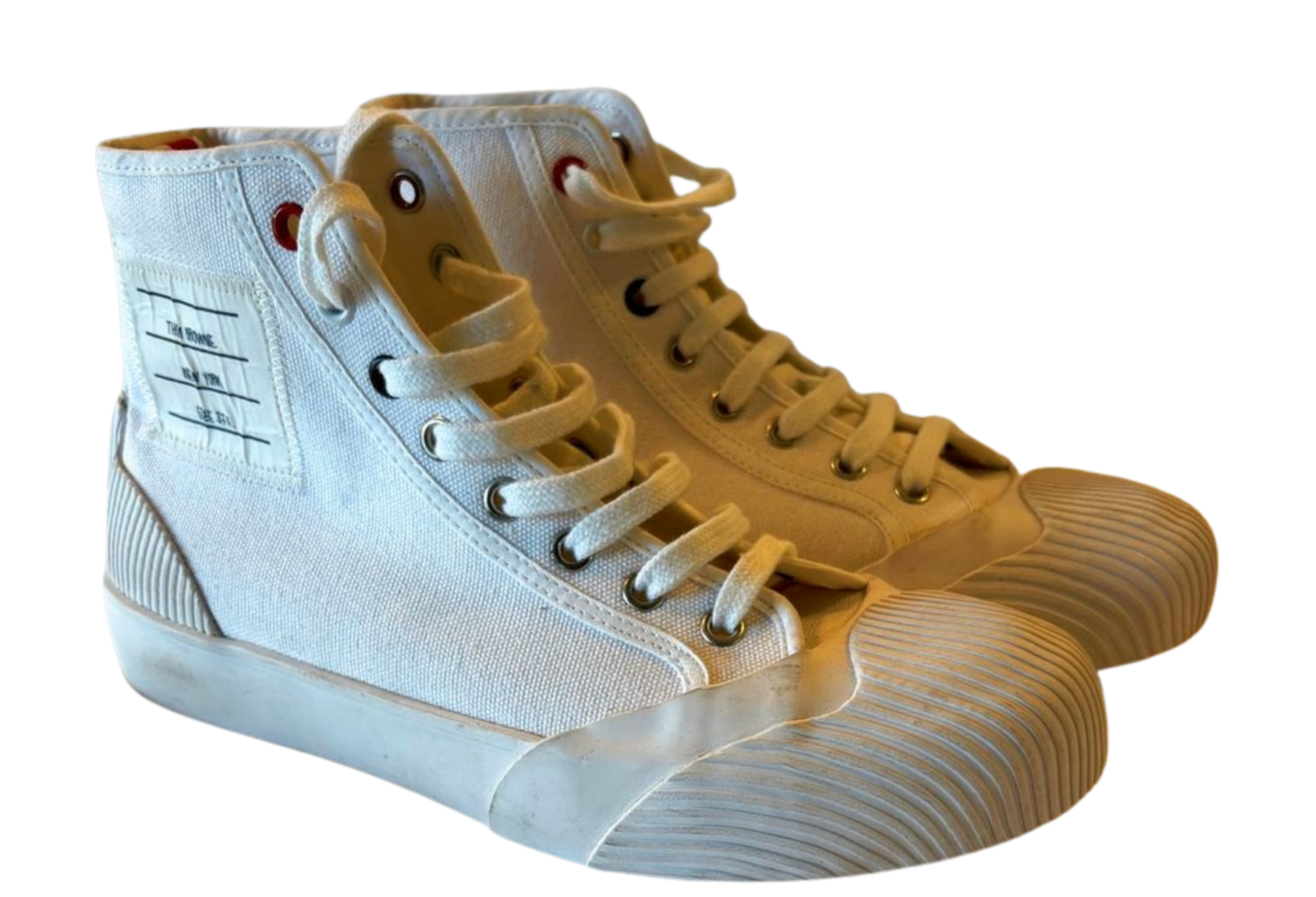 Pair of white high-top sneakers with beige laces on a white background