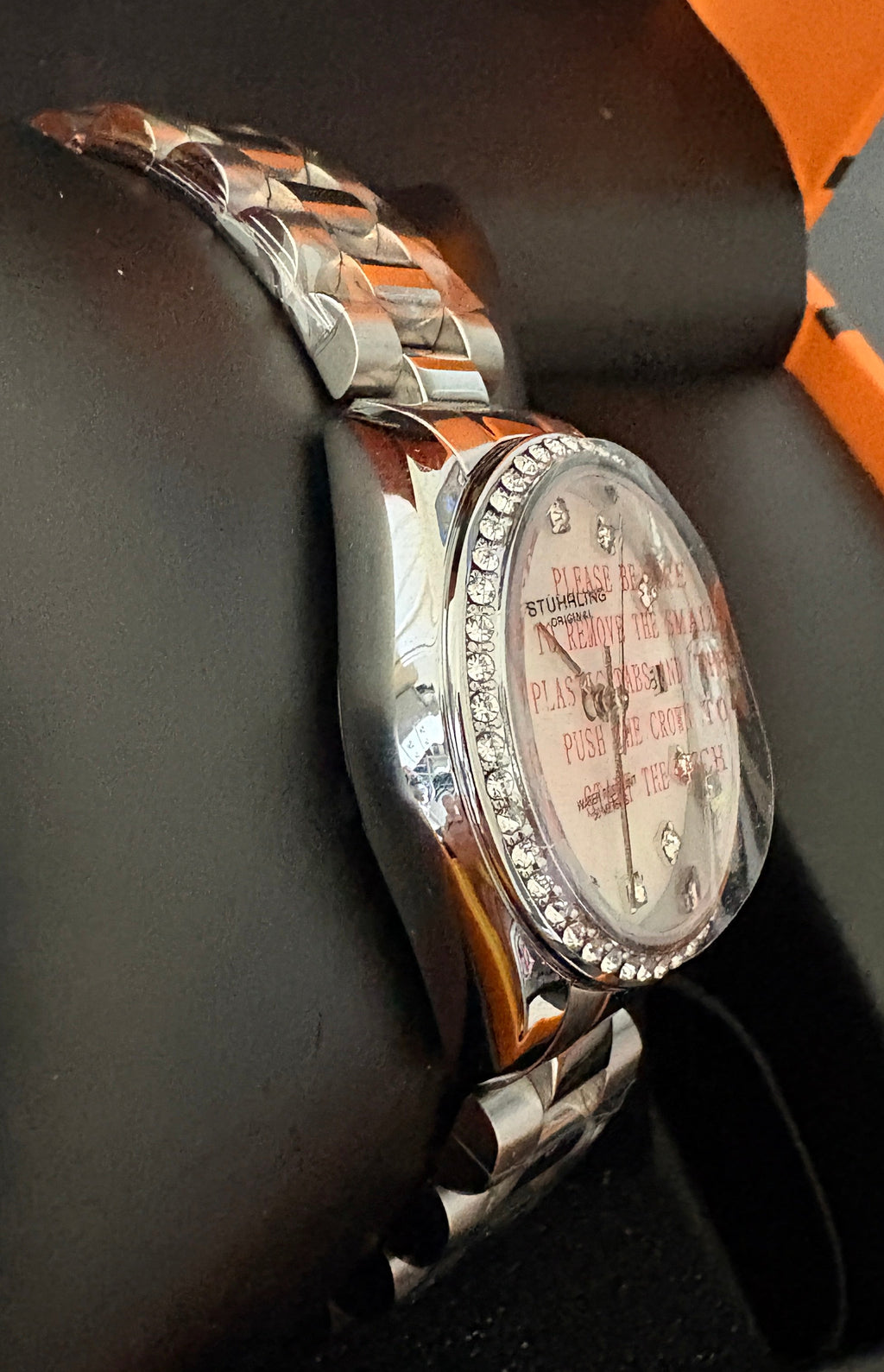 Silver wristwatch with decorative band on a black surface