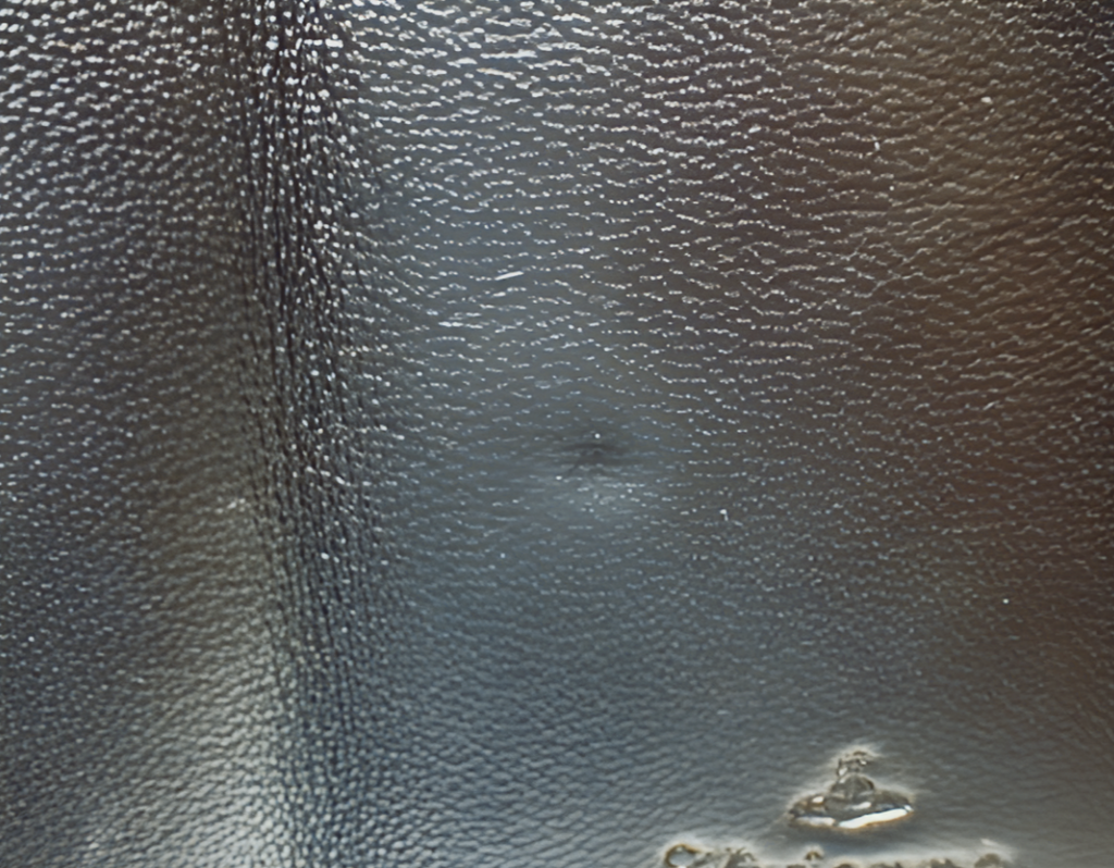 Close-up of a textured black leather surface with a brand logo.
