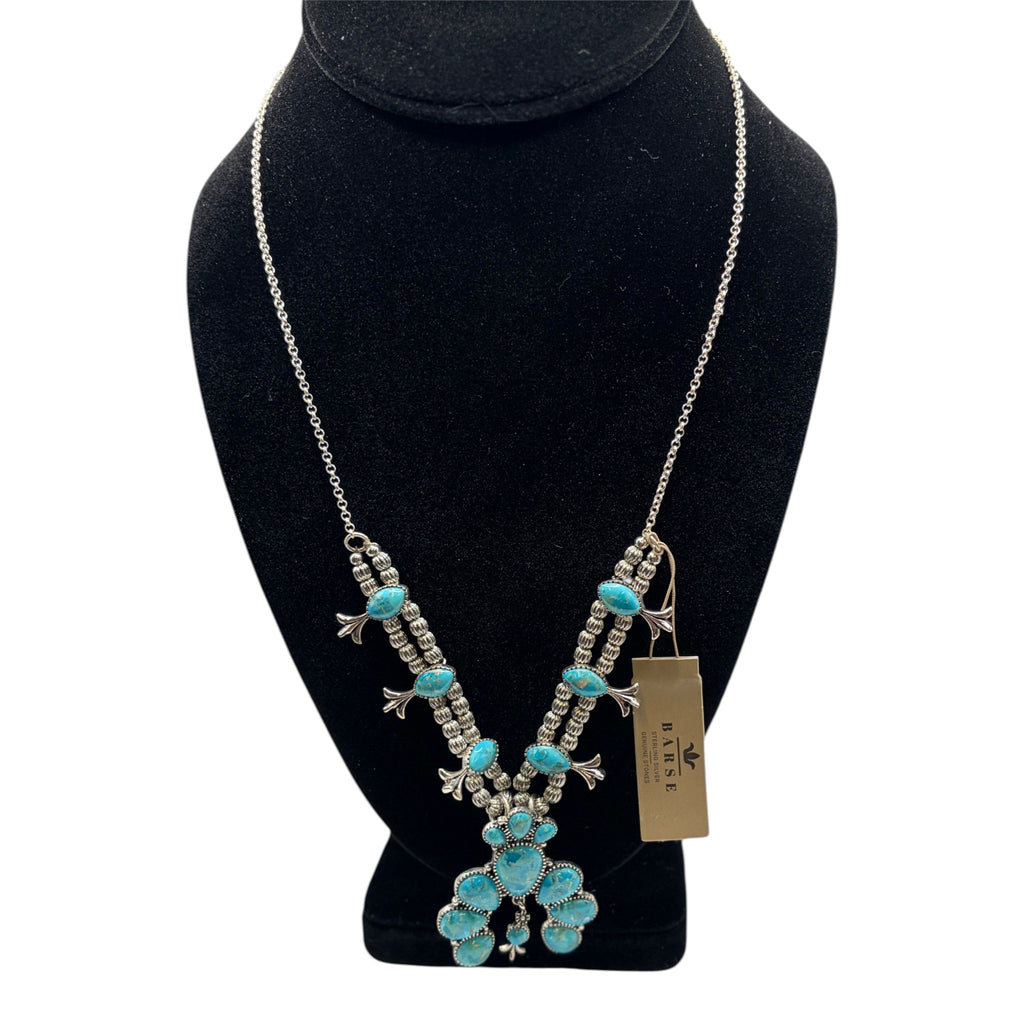 CURATED by Kira Barse sterling silver squash blossom necklace featuring teal turquoise stones on a black display bust