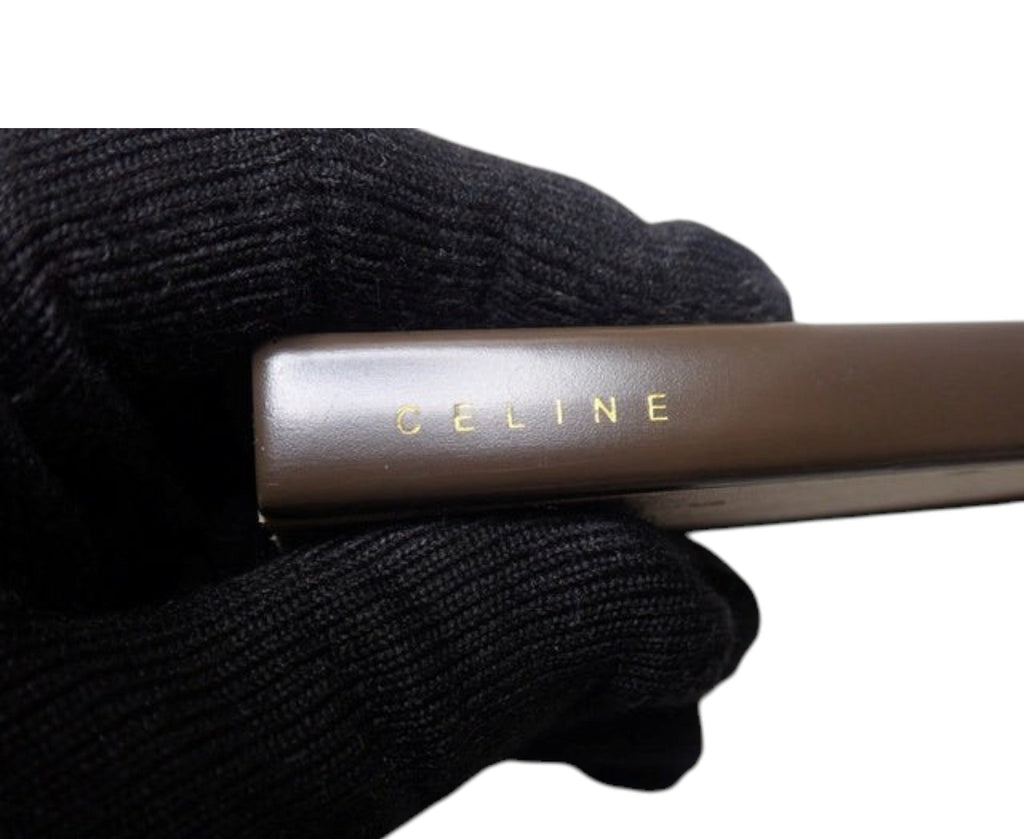 CURATED by Kira Celine folding fan storage box in dark brown with gold logo lettering held by a gloved hand