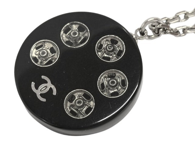CURATED by Kira Chanel Coco Tire necklace with silver chain and black pendant featuring the Chanel logo.