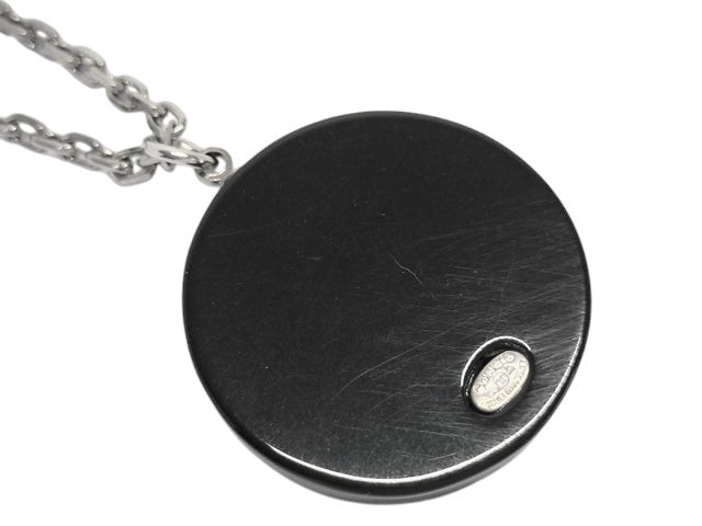 CURATED by Kira Chanel Coco Tire necklace with a silver chain and a black pendant featuring a small silver Chanel logo.