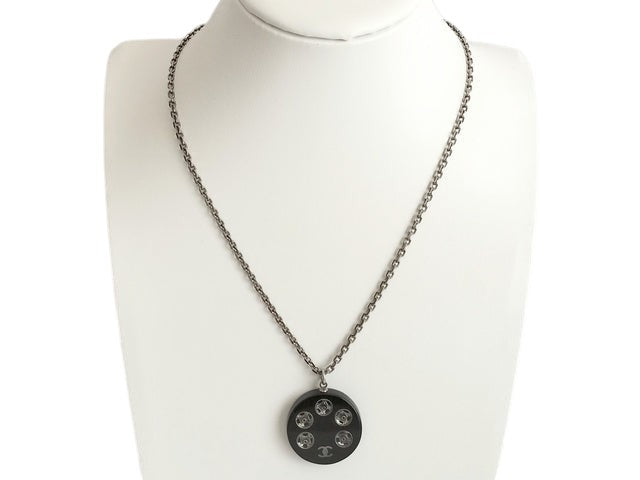 CURATED by Kira Chanel Coco Tire necklace with silver chain and black pendant featuring five clear crystals and Chanel logo.