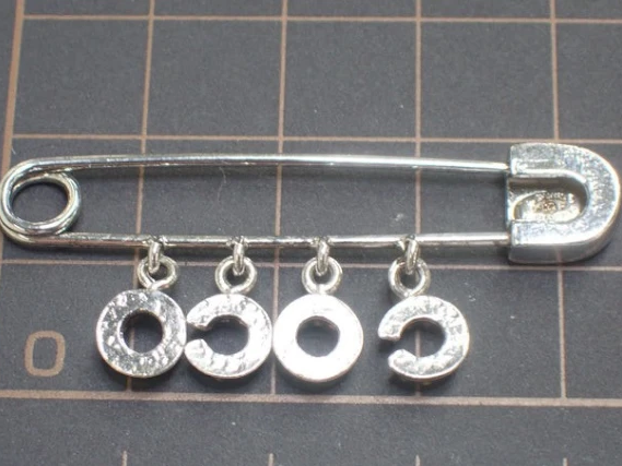 CURATED by Kira Chanel Icon Series silver safety pin brooch featuring dangling COCO letter charms