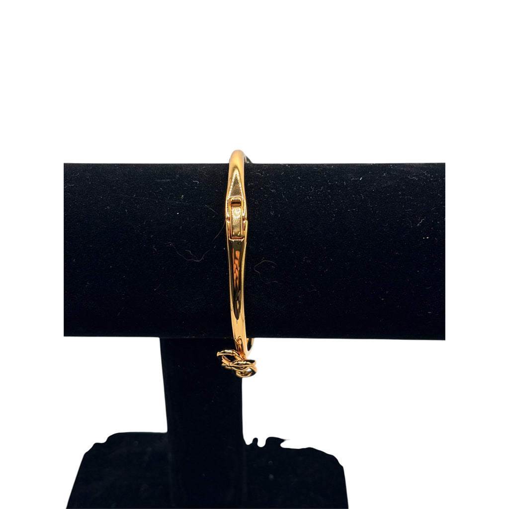 CURATED by Kira gold tone Kate Spade hinged bangle bracelet featuring a delicate bow knot design on a display stand