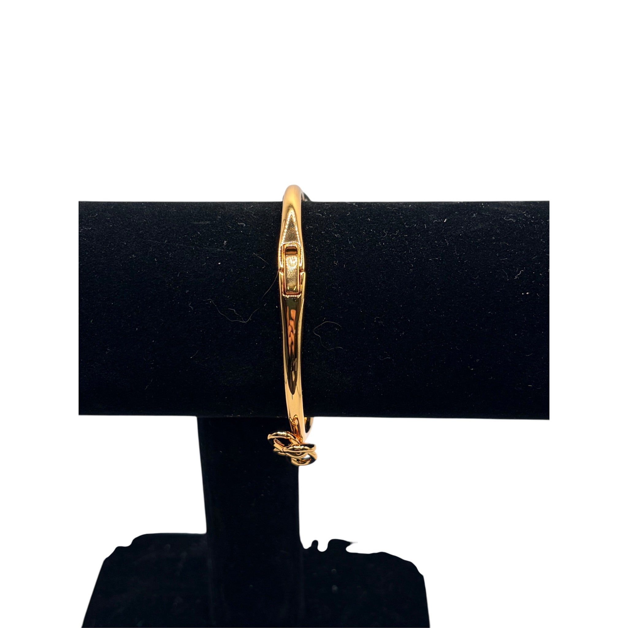 CURATED by Kira gold tone Kate Spade hinged bangle bracelet featuring a delicate bow knot design on a display stand