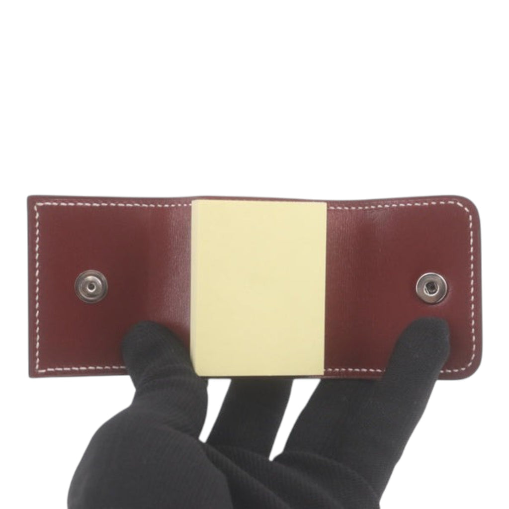 CURATED by Kira Hermes maroon leather notepad with snap button closure held by a gloved hand