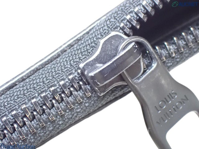 Close-up of the metal zipper pull with Louis Vuitton branding on a brown zipped pouch from CURATED by Kira
