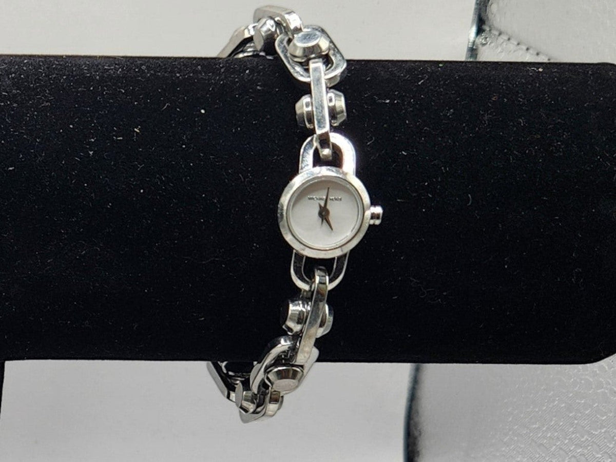 CURATED by Kira Michael Kors Astor silver stainless steel chain-link bracelet watch with white dial on display stand