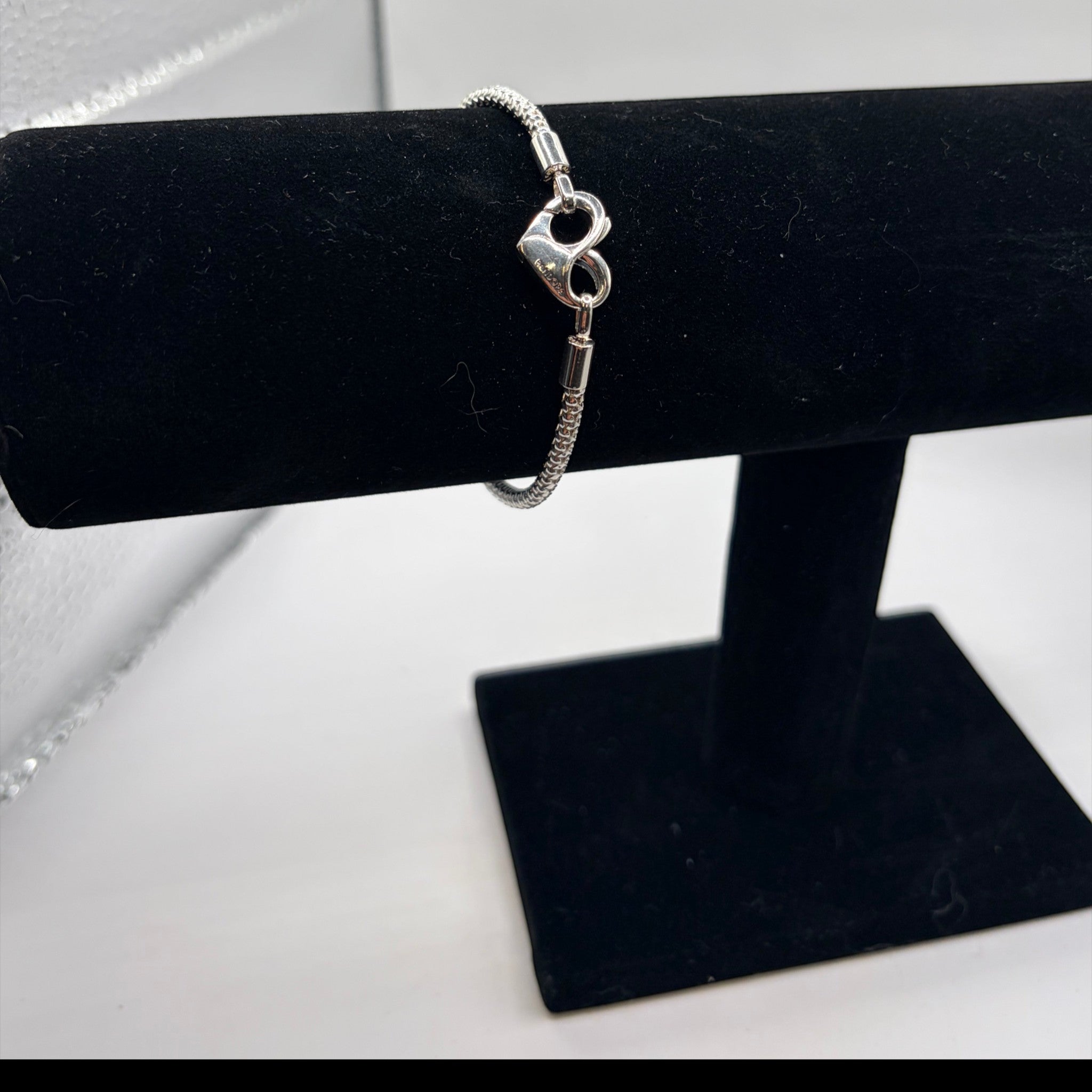 CURATED by Kira Pandora sterling silver bracelet featuring a heart-shaped clasp on a black velvet display stand