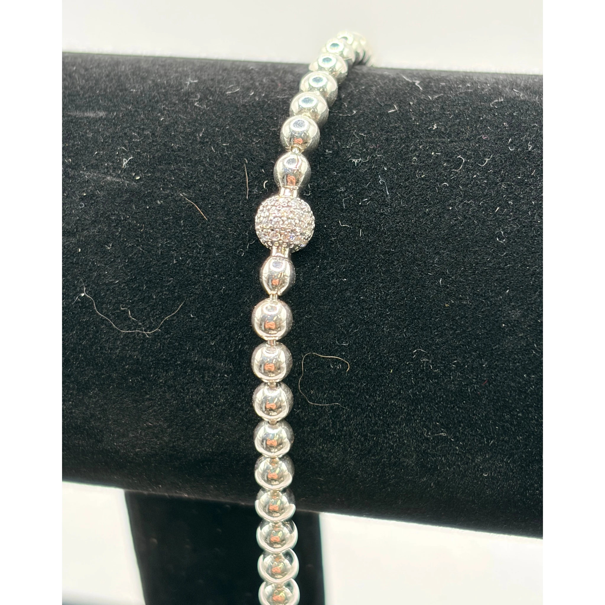 CURATED by Kira Pandora silver tone beaded bracelet featuring a central pave crystal ball accent on a black display
