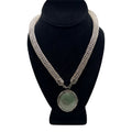 CURATED by Kira 1928 silver tone mesh choker necklace with an ornate oval green gemstone pendant on a display bust