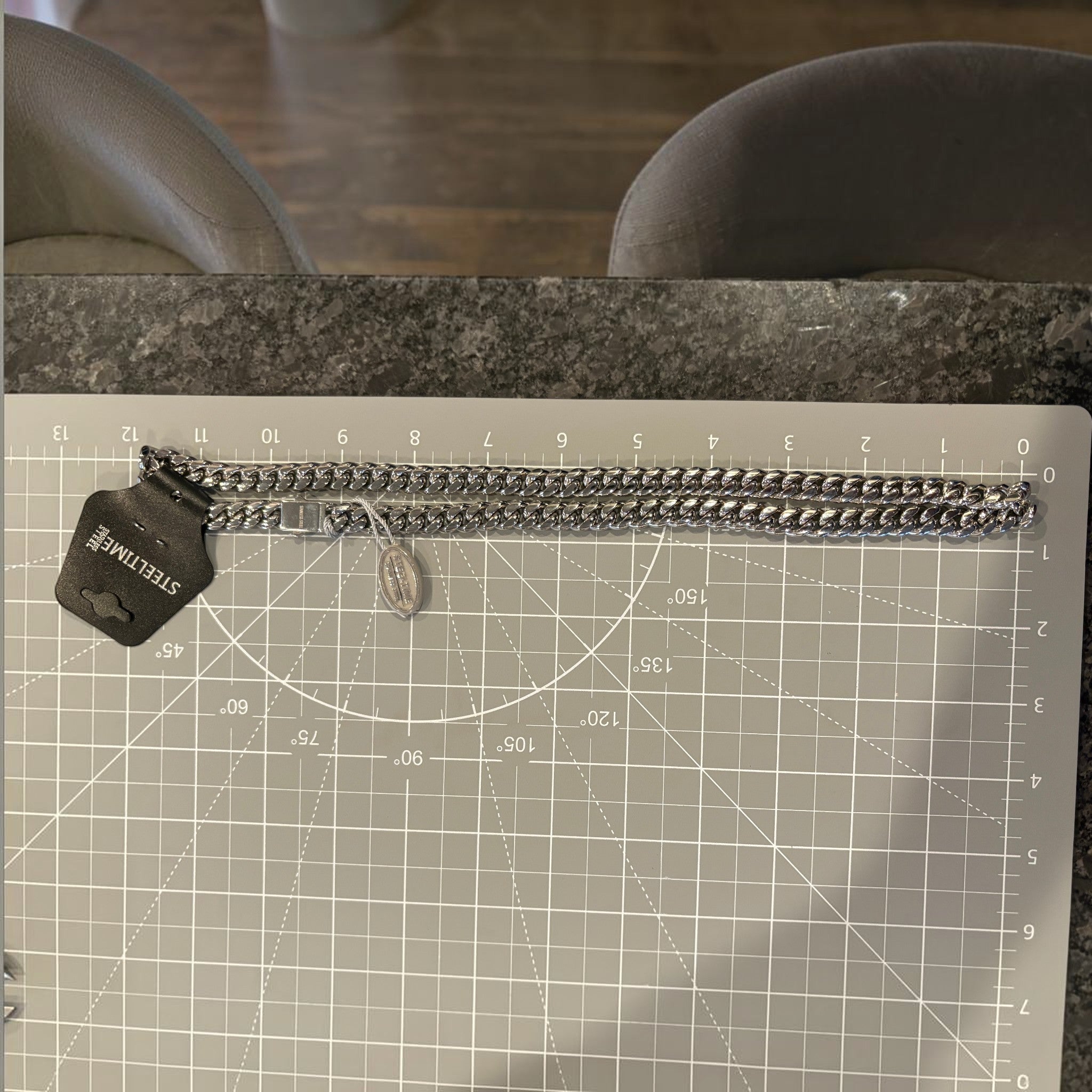 CURATED by Kira Steeltime silver-tone stainless steel curb link chain necklace with a polished finish on a cutting mat.