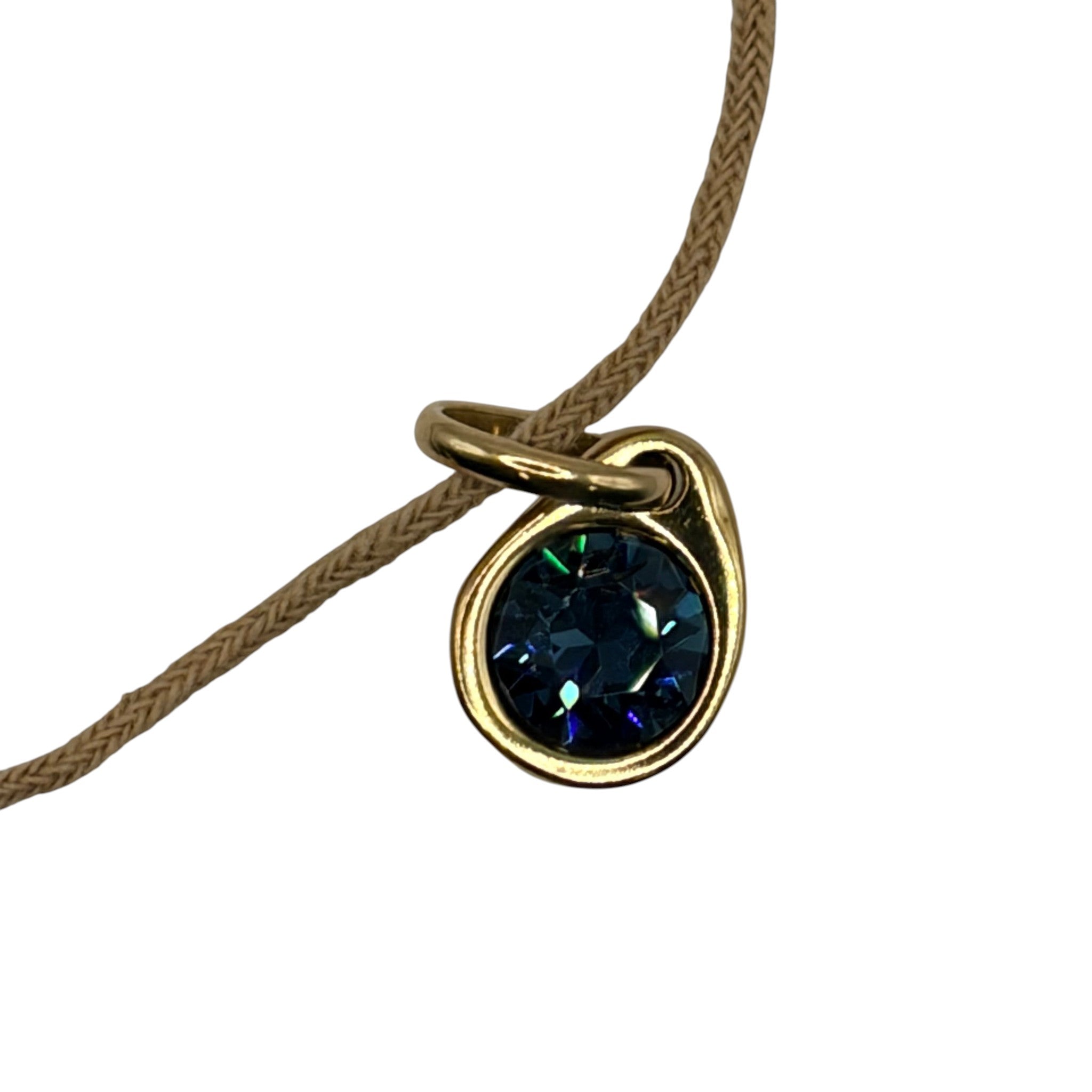 CURATED by Kira Uno de 50 gold tone charm with a faceted dark green crystal drop on a beige cord