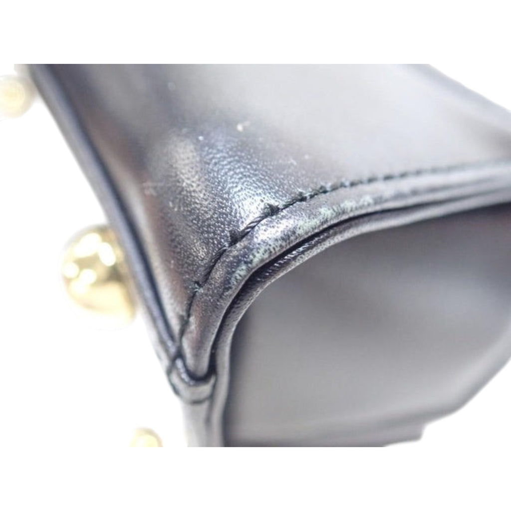 CURATED by Kira Vivienne Westwood black enamel handbag showing close-up of stitched leather corner and gold hardware