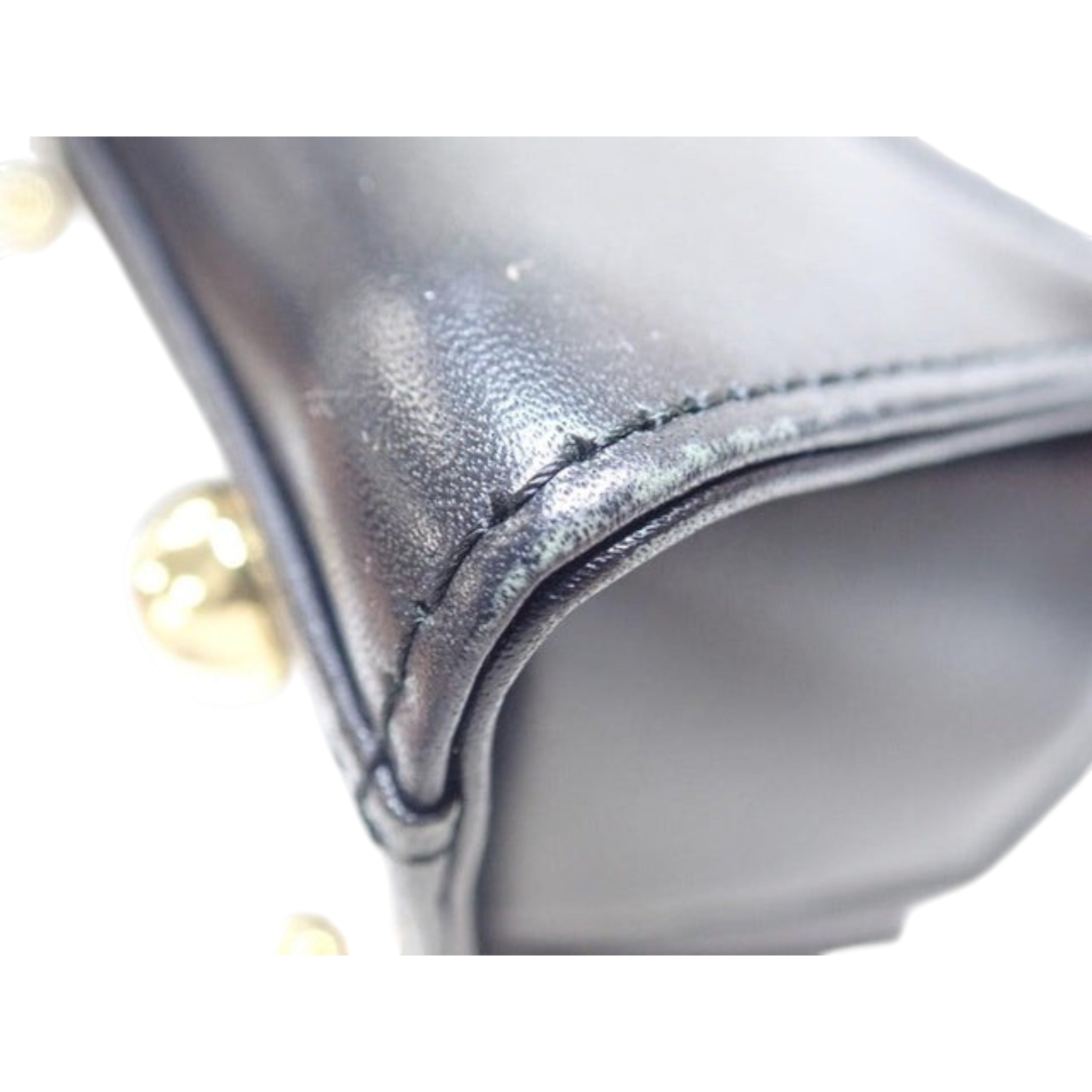 CURATED by Kira Vivienne Westwood black enamel handbag showing close-up of stitched leather corner and gold hardware