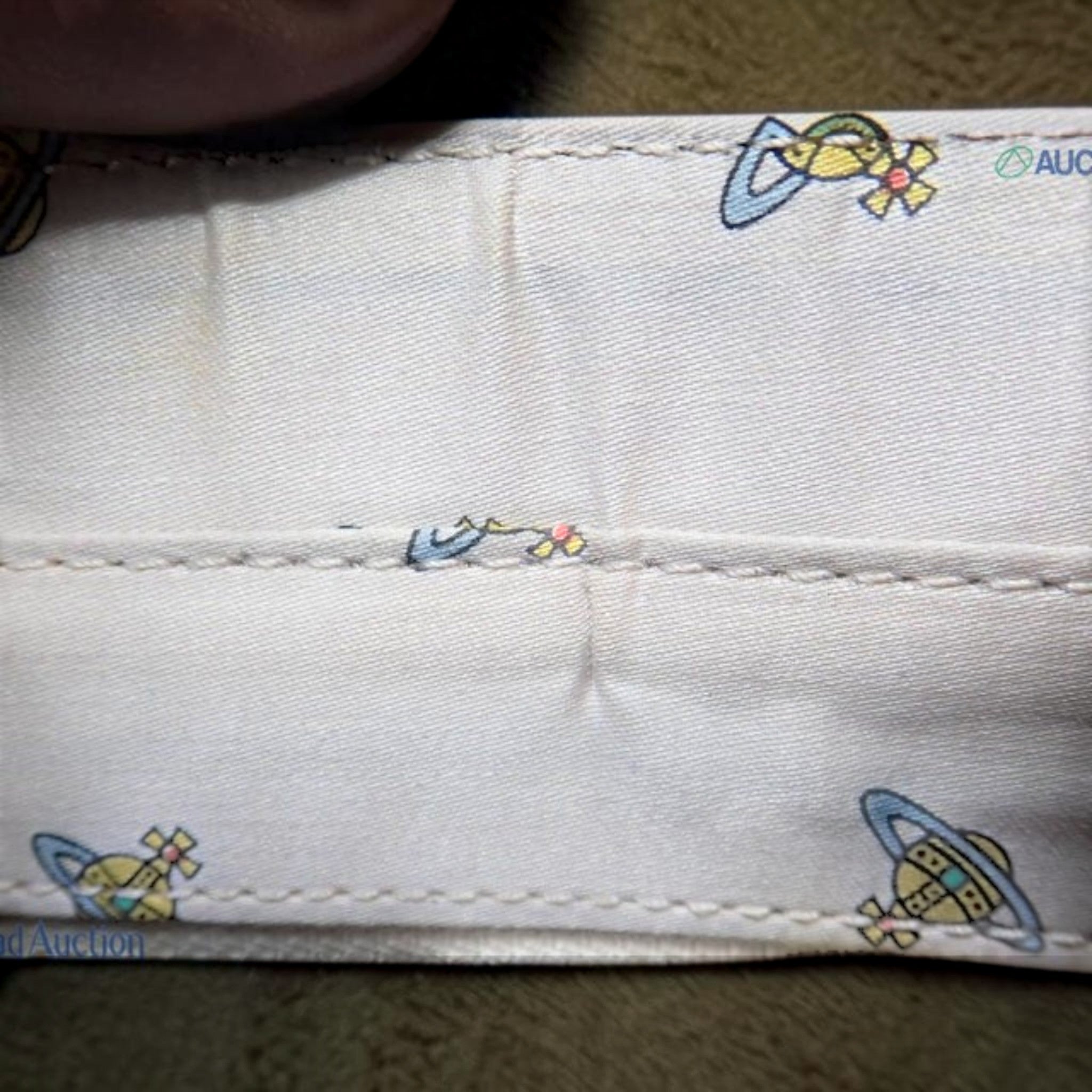 CURATED by Kira Vivienne Westwood handbag interior lining featuring the iconic orb logo pattern on cream fabric