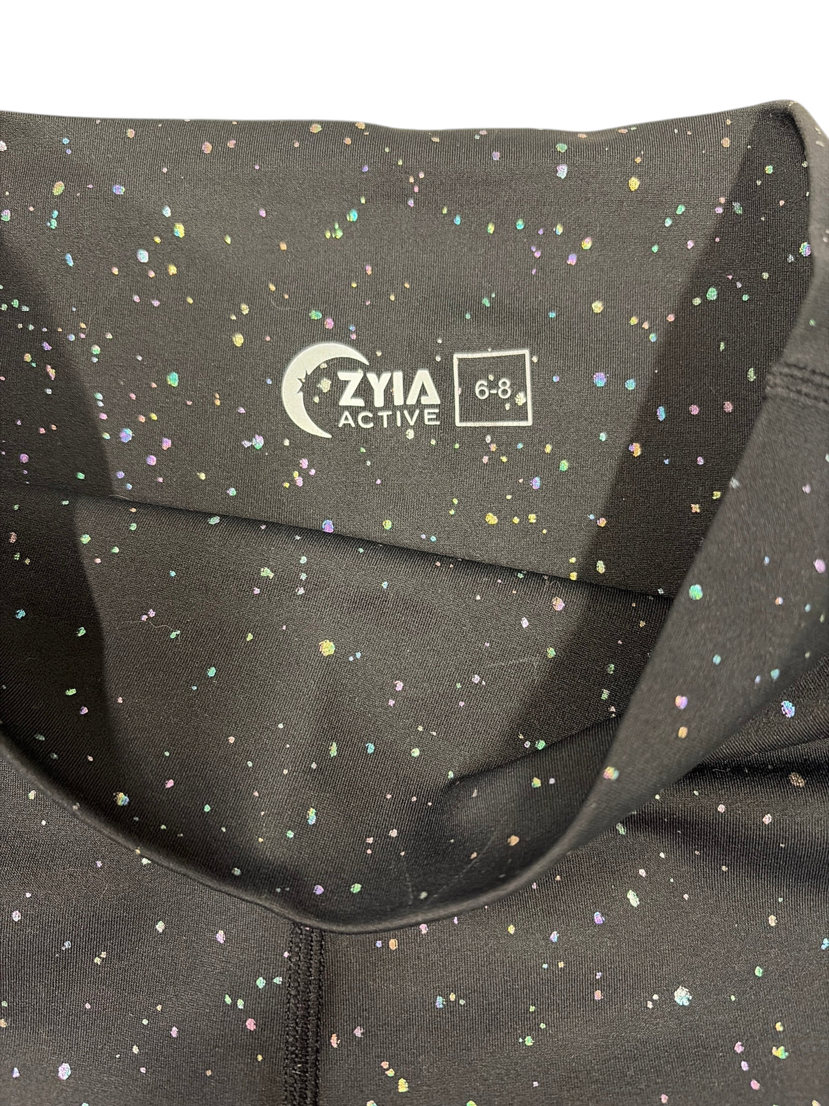 CURATED by Kira ZYIA Active black high-waisted leggings featuring an iridescent metallic speckle pattern and logo.